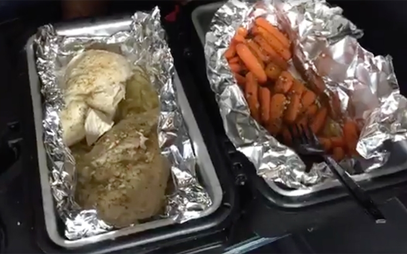 An electric lunch box opens to a hot homecooked meal of carrots and chicken.