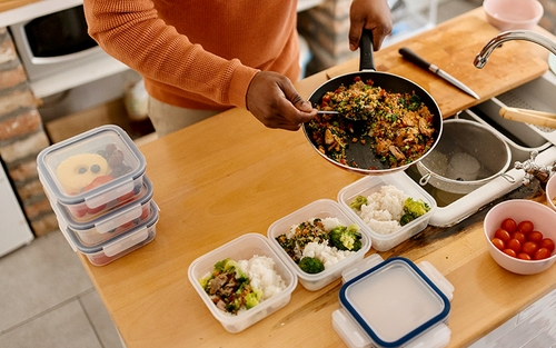 A truck driver meal prepping by portioning their food into Tupperware containers.