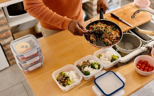 A truck driver meal prepping by portioning their food into Tupperware containers. 