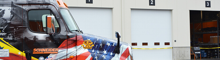 A Schneider Ride of Pride truck dedicated to honoring our nation's veterans waits outside the service bays of a company diesel shop