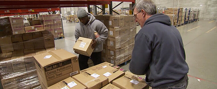 Two Schneider warehouse associates load pallets with packages