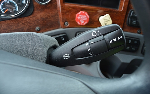 A black automatic manual transmission gear shift, located on the right hand side of the truck steering column, set to drive.