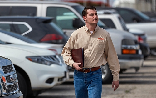 A man walking and holding a leather portfolio.