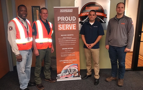 Intermodal driver Don Antle, Operations Manager Corey Dyke and Senior Instructor Willie Henderson stand by a Schneider military recruitment poster.