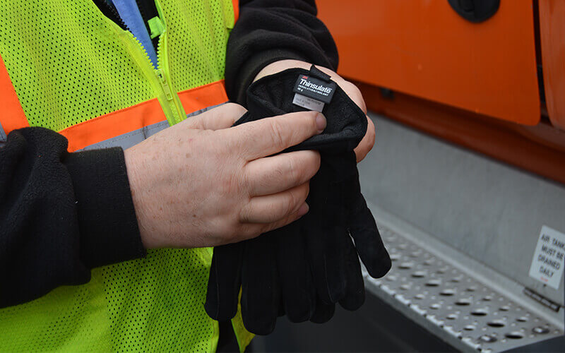 A truck driver slips on a pair of winter gloves.
