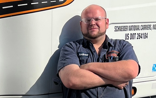Schneider Senior Diesel Technician Andrew Mercer standing in front of a semi-truck with his arms crossed.