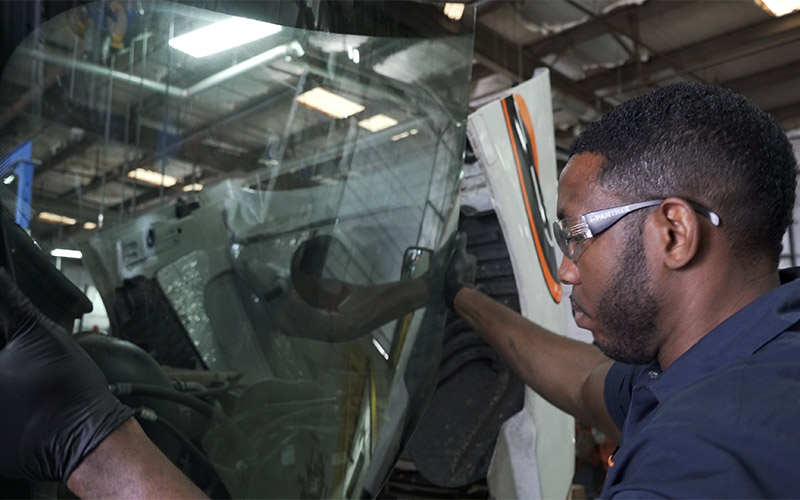 A Schneider diesel technician places a windshield on a Schneider truck.