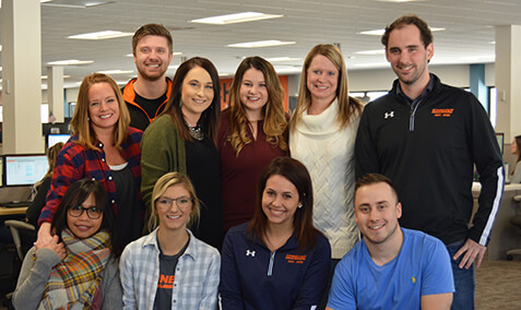 Ten Schneider Transportation Management associates pose together in an office facility