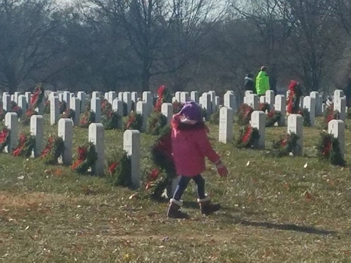 Children laying wreaths on graves at a cemetery for Wreaths Across America.