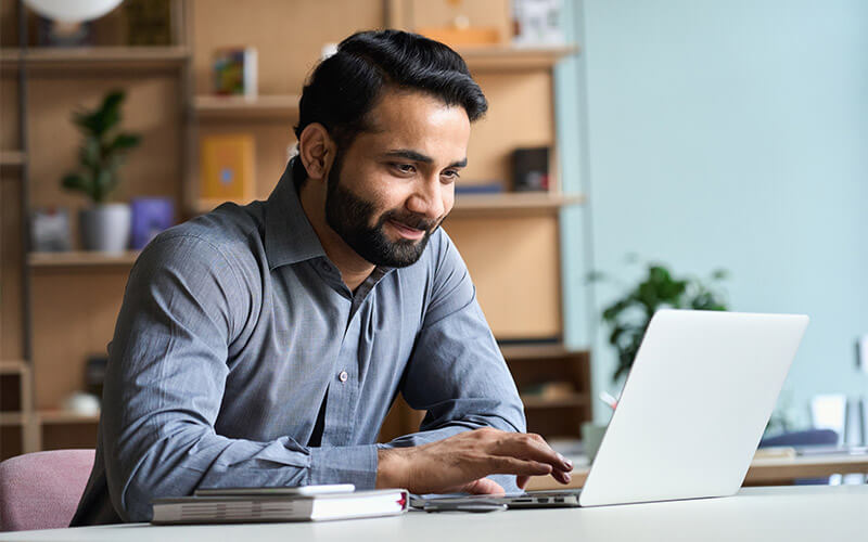 A adult learner working on his coursework online from a laptop.