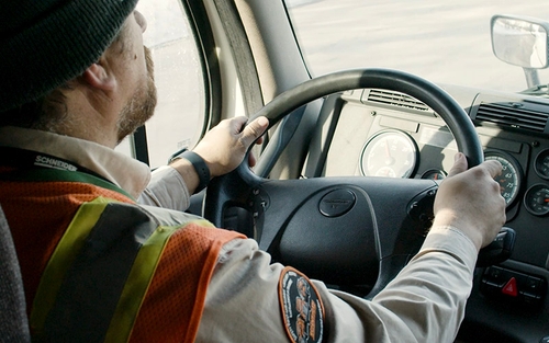 A Schneider Driver Instructor behind the wheel of a semi-truck.