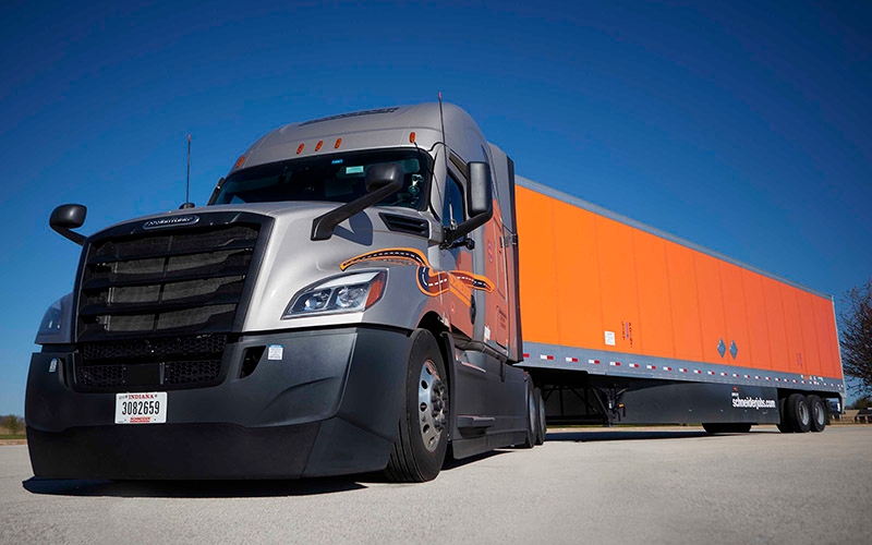 A parked Schneider semi-truck under a clear sky. 