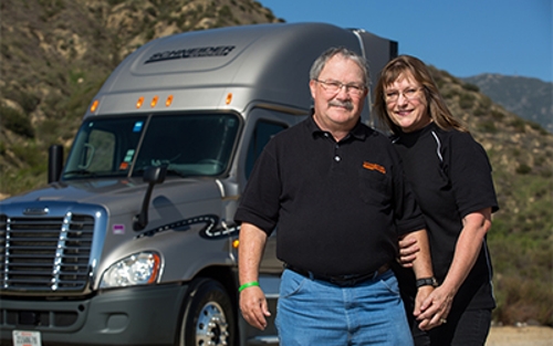 A married couple poses with their truck as Schneider team drivers.