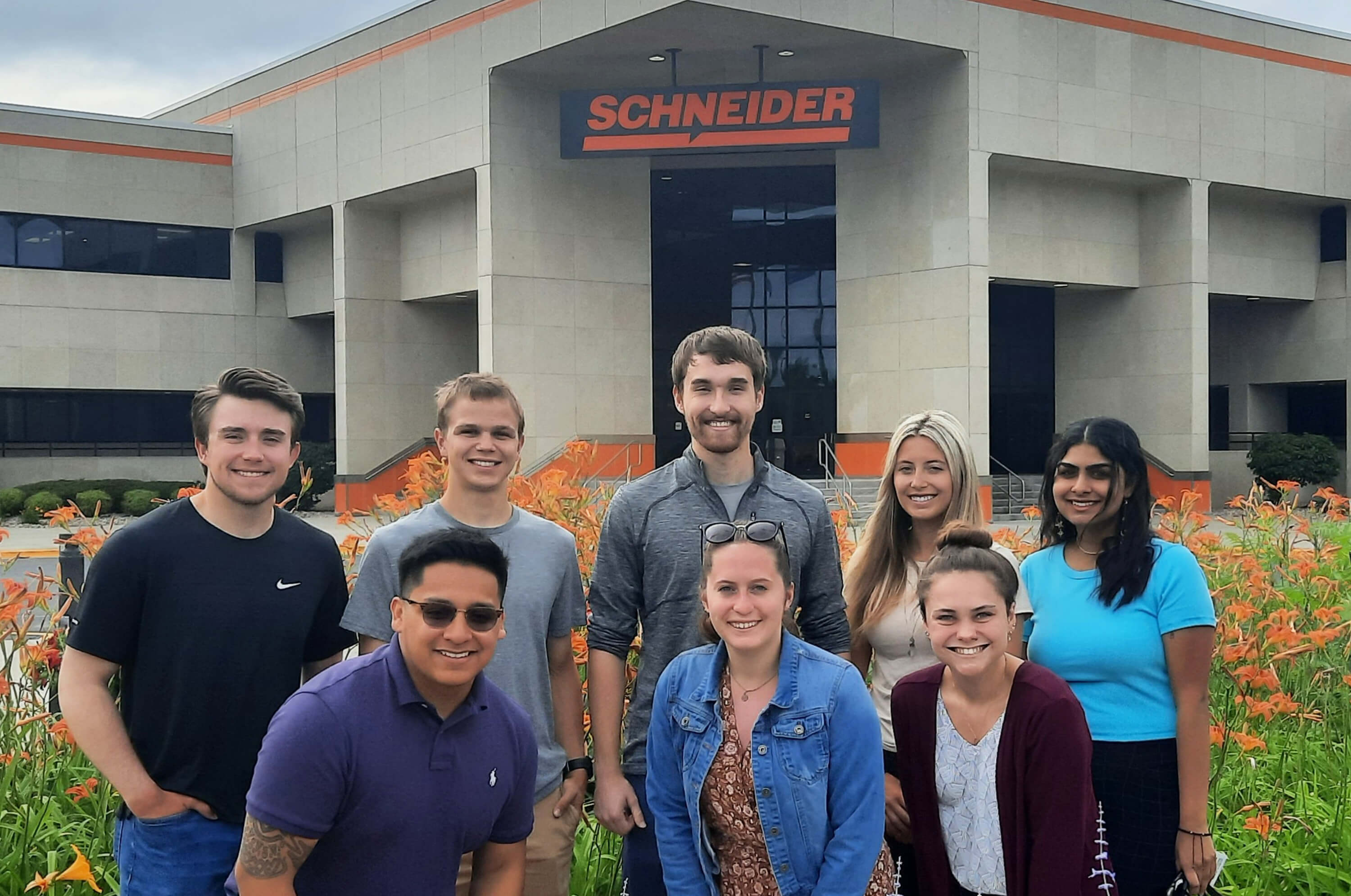 Eight Schneider interns pose together outside Schneider's corporate office in Green Bay, Wisconsin