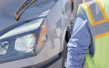 A female Schneider driver looks at the hood of her truck.