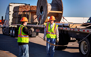 A truck driver trainer teaches a student how to secure a load.