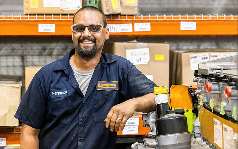 A man stands next to equipment in a maintenance shop.