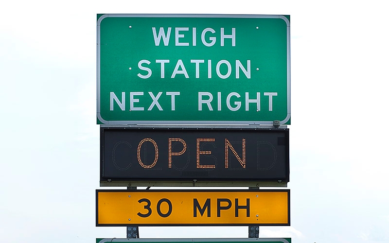 A green road sign for an open weigh station reading "weigh station next right."