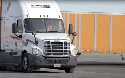 A Schneider semi-truck in the process of backing up.