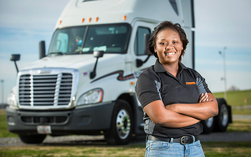 Schneider driver Keisha Orange poses with arms crossed in front of her company truck