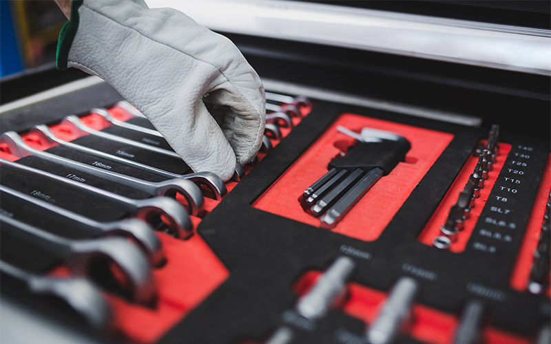 A hand reaching for tools in a toolbox.