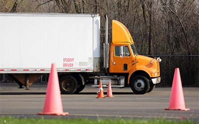A Schneider company truck parked in a driving course lined with traffic cones