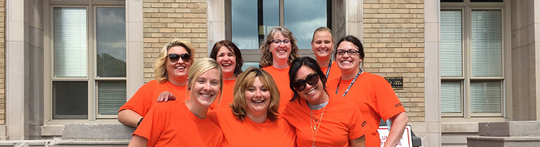 Eight members of the Schneider Women's Network pose together at an event in matching t-shirts