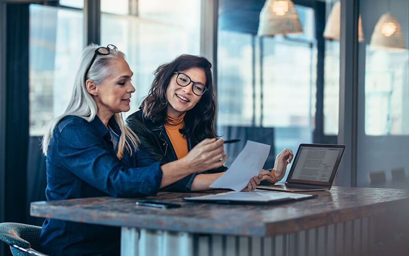 A mature associate and millennial collaborate in a conference room