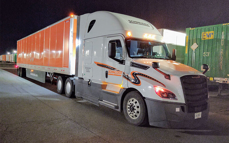 Mike and Cameron's Schneider truck parked in a freight yard.