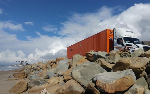 An Schneider Intermodal driver drives along the beach.