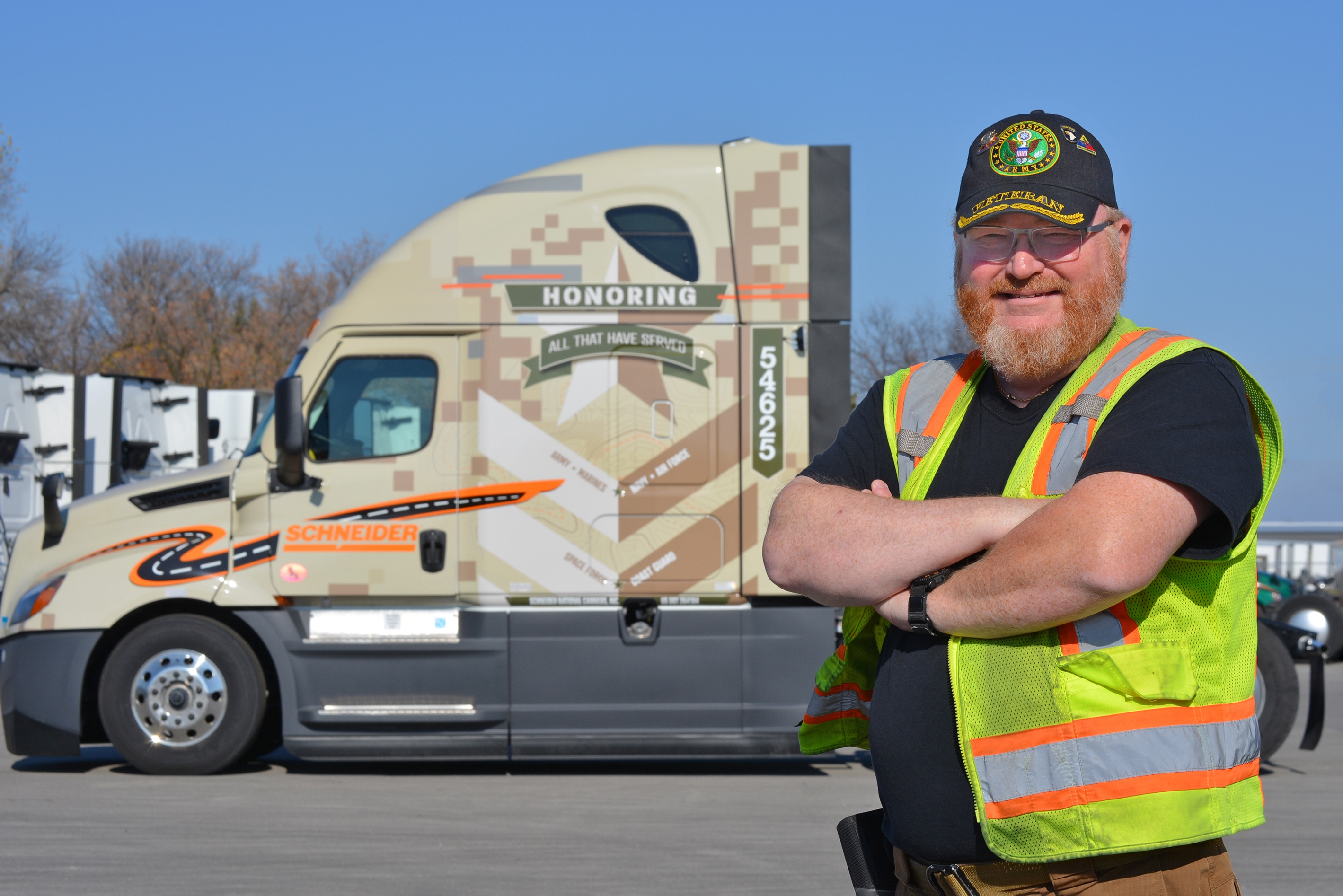Bobby Brown standing in front of Schneider's newest military-wrapped truck.
