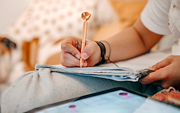 A woman uses a fancy gold pen to write in a notebook.