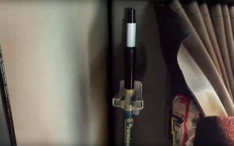 A adhesive hanger being used to hold a broom in the cab of a semi-truck.