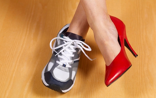 A woman wears a red high heel shoe on her right foot and a white and grey sneaker on her left foot, signifying the importance of balancing work and life.