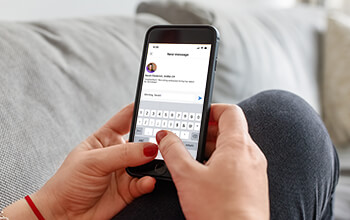 A close up on a woman's hands that are typing out a LinkedIn message on a smart phone.