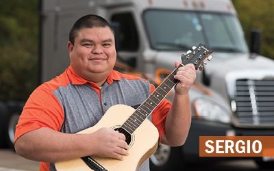 Sergio strums the guitar in front of the company truck he shares with his brother.