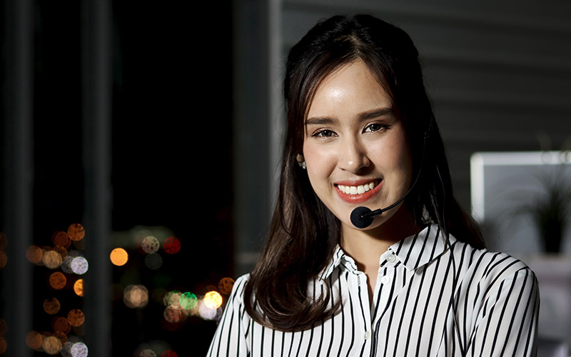 A woman with a headset looking forward and smiling.