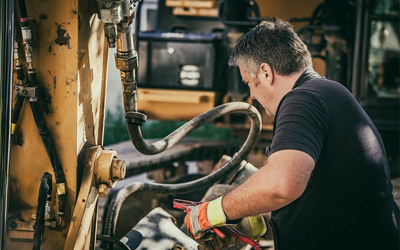 A man working on heavy machinery inside a shop.