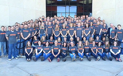 Schneider associates donning matching t-shirts gather on the front steps of a Schneider facility.