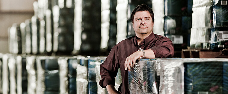 A Schneider associate poses next to rows of pallets in a company warehouse