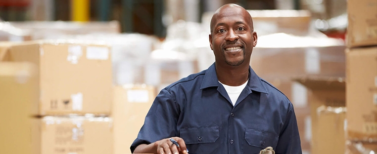 A Schneider associate poses next to rows of boxes and pallets in a company warehouse