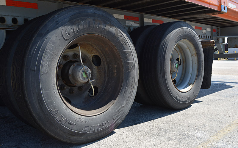 Four radial Good Year tires are attached to the back left-hand side of an Intermodal trailer. The thin tubes of the automatic tire inflation system come from the center of each tire hub and connect to the interior of the tire hub caps.