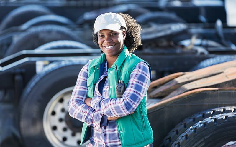 A truck driver poses in front of a row of unladen trucks.