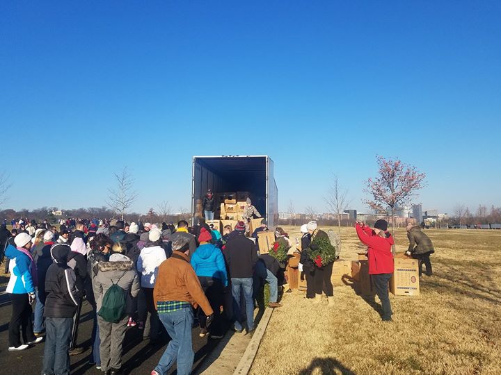 Volunteers unload wreaths from a trailer for Wreaths Across America.