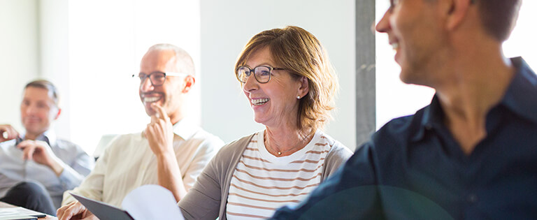 A Schneider human resources associate smiles brightly at a conference table while she is surrounded by colleagues