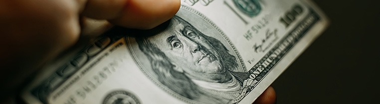 A truck driver holds a stack of $100 bills after payday