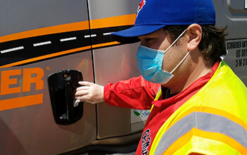 A Schneider driver wipes down the door handle on his truck.