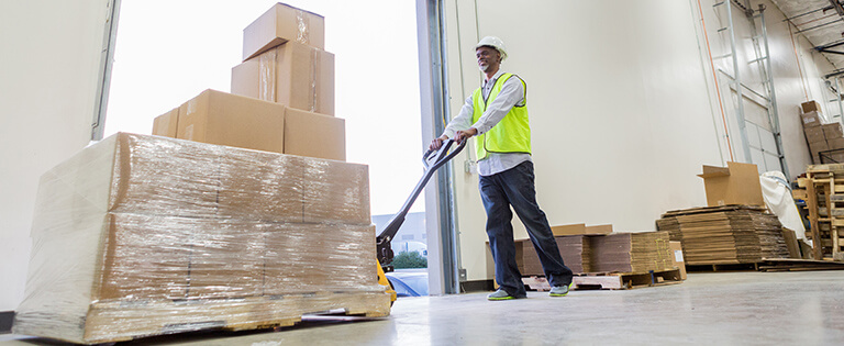 A Schneider warehouse associate moves a pallet of boxes to a loading dock