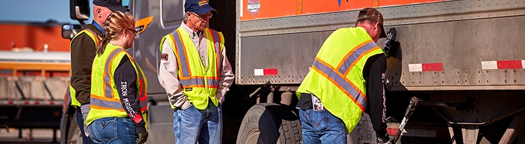 A driver instructor and three new drivers practice raising the landing gear on the trailer