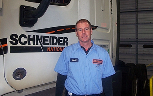 John McMurry stands in the service bay with a Schneider truck.